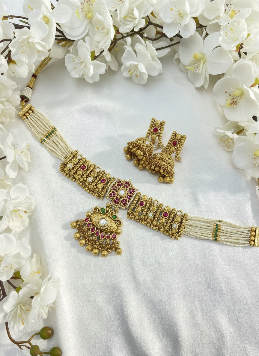 Gold jewelry set with necklace and earrings on a white fabric background