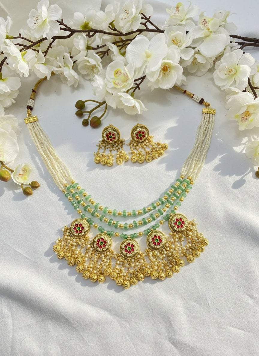 Gold necklace with green beads on a pink fabric background