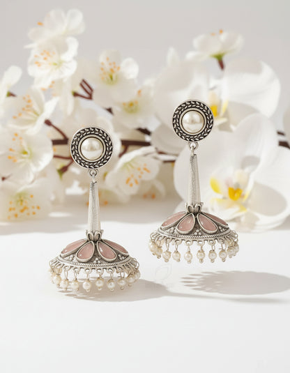 Pair of silver earrings with pearl-like beads on a brown background