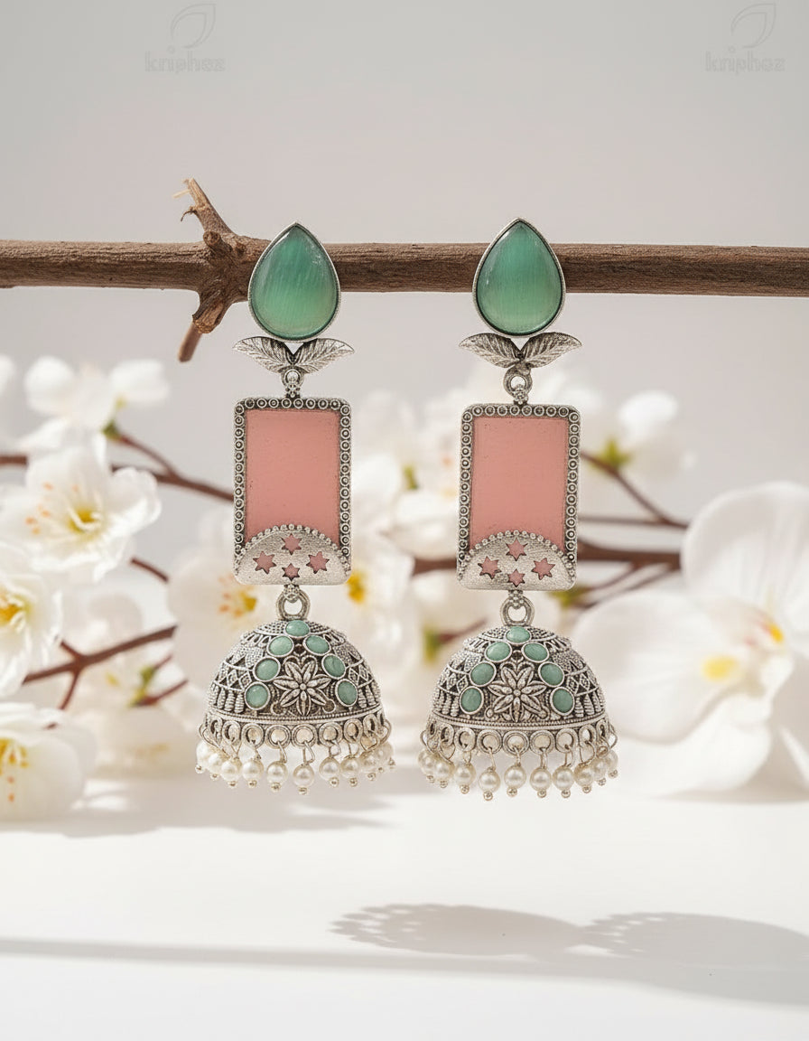 Ornate earrings with pink and green stones on a branch