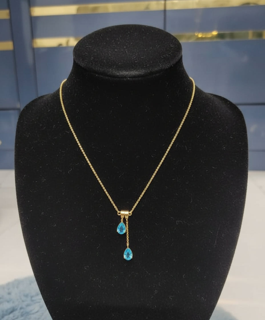Gold necklace with blue stones on a mannequin bust against a blue background