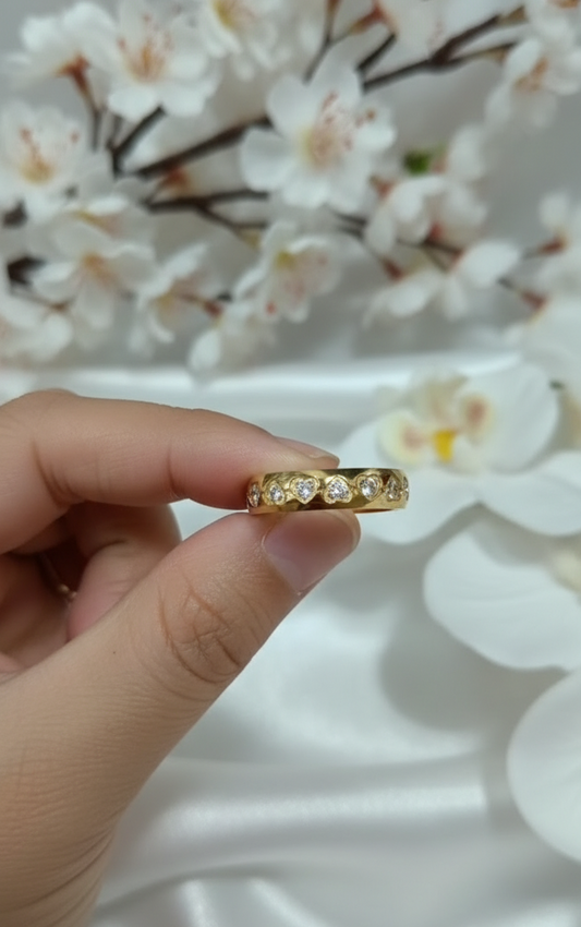Gold ring with diamonds on a finger against a white background
