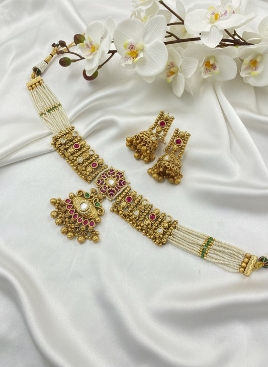 Gold jewelry set with necklace and earrings on a white fabric background