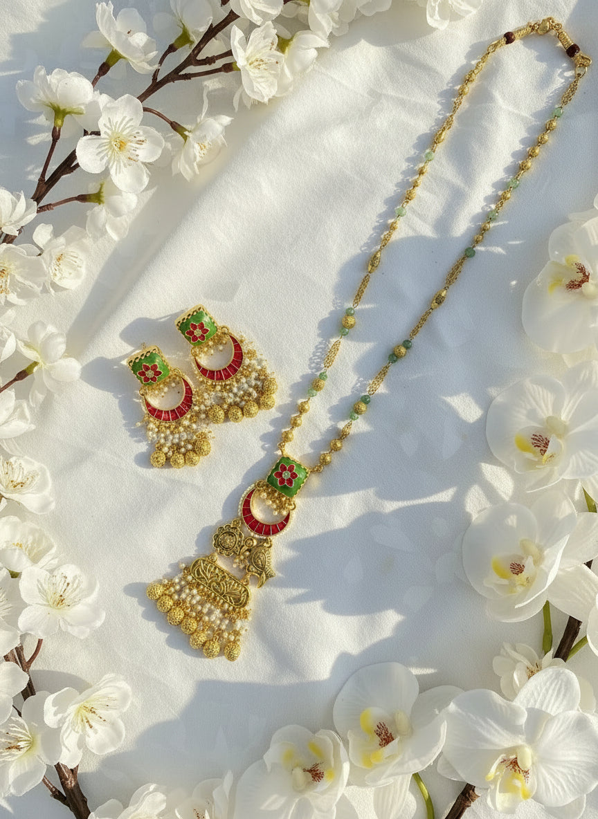Gold necklace with green beads and matching earrings on a pink and white background