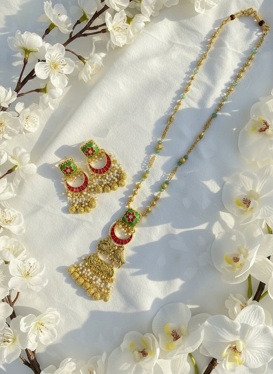 Gold necklace with green beads and matching earrings on a pink and white background