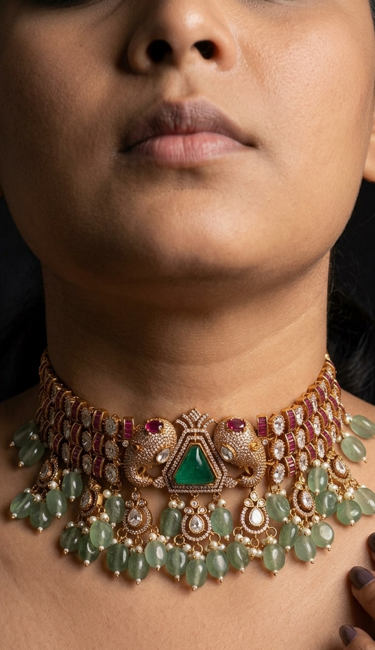 Close-up of a person wearing an ornate necklace with green gemstones and red stones.