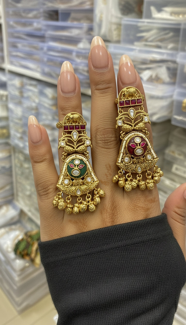 Gold rings with intricate designs on a hand against a blurred background