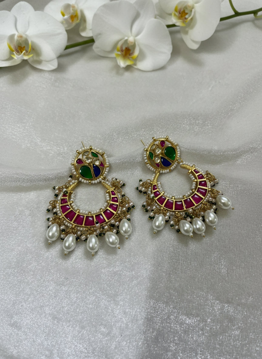 Ornate earrings with gemstones and pearls on a light gray background