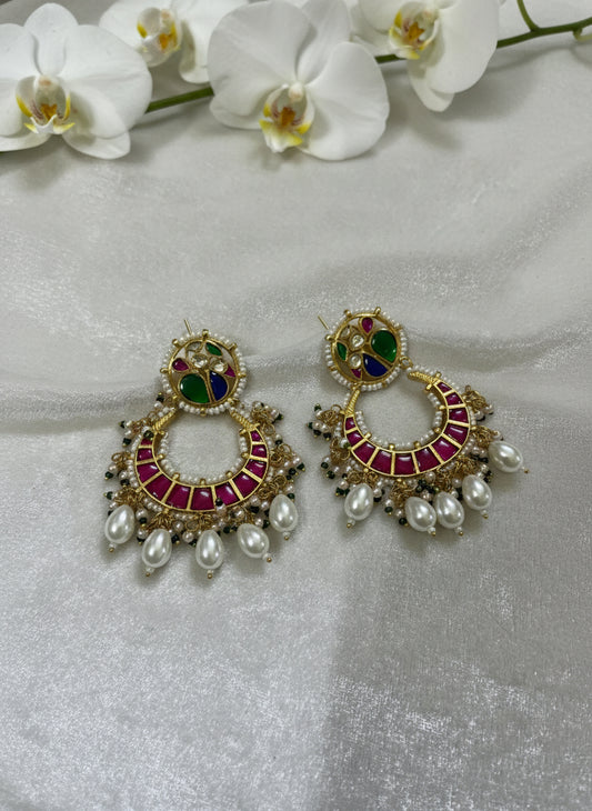 Ornate earrings with gemstones and pearls on a light gray background
