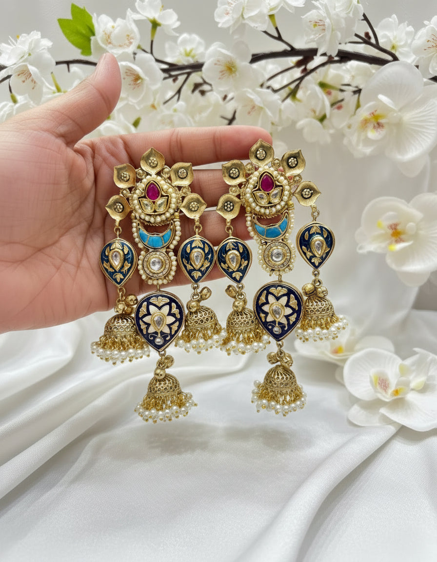 Ornate earrings held by a hand with a white floral background