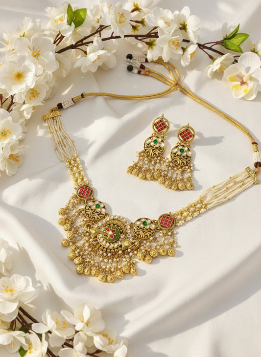 Gold necklace and earrings on a pink and gray background