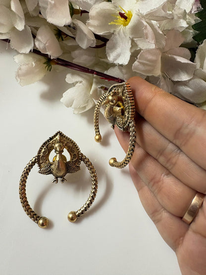Gold earrings held by a hand with white flowers in the background