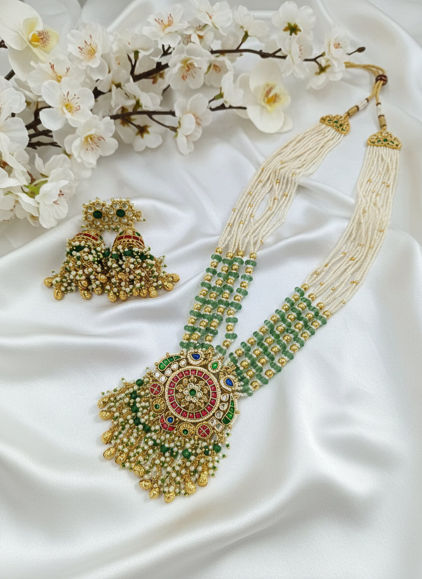 Ornate necklace and earrings with green and gold details on a white background