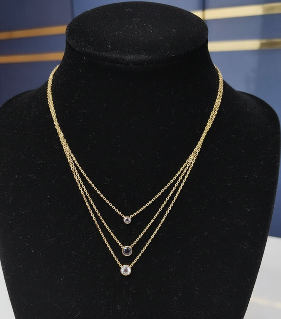 Gold necklace with black beads on a mannequin bust against a blue background