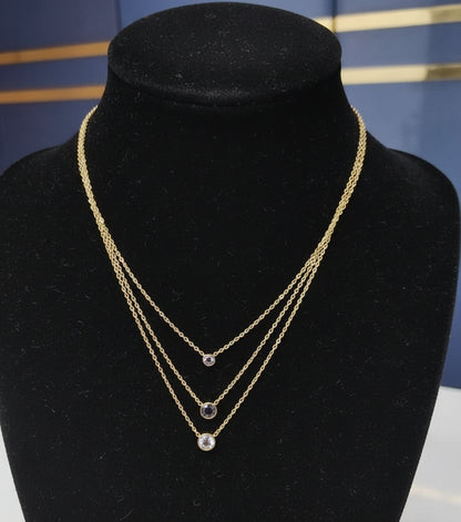 Gold necklace with black beads on a mannequin bust against a blue background