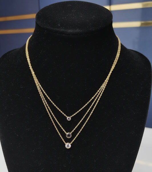 Gold necklace with black beads on a mannequin bust against a blue background
